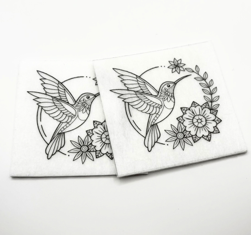 Two beading patterns printed in black on stiff white pellon squares, showing a hummingbird in a floral wreath