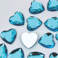 Pile of 20mm faceted aqua resin heart gem cabochons (cabs), one flipped to show the flat back