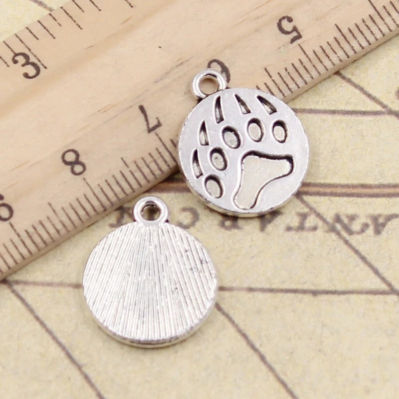 18x15mm antique silver circle bear paw charms next to a ruler