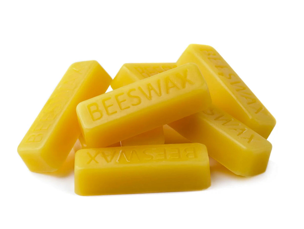 Several small yellow 1 oz beeswax bars stacked together on a white background