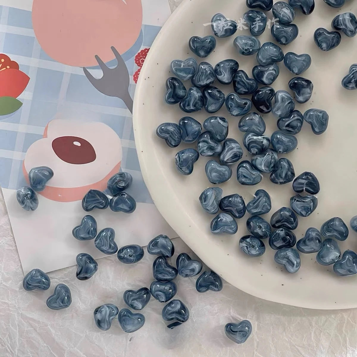 Bowl of 10 x 12mm blue swirl heart acrylic beads with a marbled clear finish