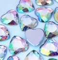 Pile of 20mm faceted Crystal AB resin heart gem cabochons (cabs), one flipped to show the flat back