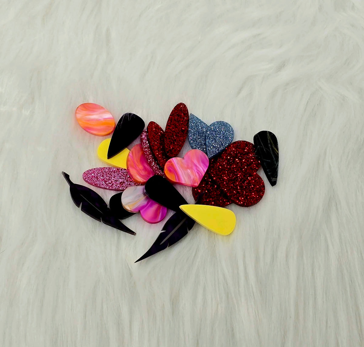 Pile of about 10 random pairs of acrylic cabochons (cabs) in glitter, marbled and solid colours