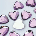 Pile of 20mm faceted lilac resin heart gem cabochons (cabs), one flipped to show the flat back