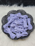 Bundles of 2.7mm periwinkle suede leather lacing coiled on a dark scalloped dish