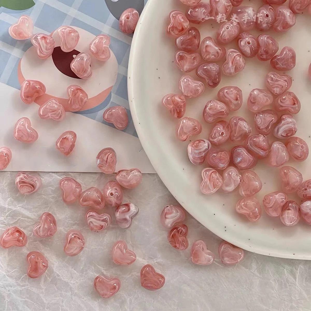 Bowl of 10 x 12mm pink swirl heart acrylic beads with a marbled clear finish