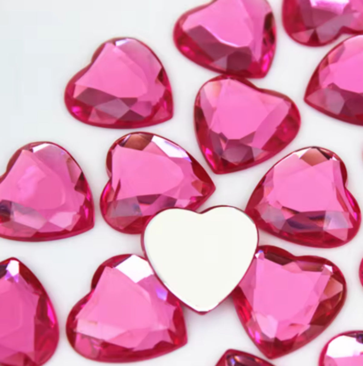 Pile of 20mm faceted pink resin heart gem cabochons (cabs), one flipped to show the flat back