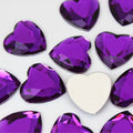 Pile of 20mm faceted purple resin heart gem cabochons (cabs), one flipped to show the flat back