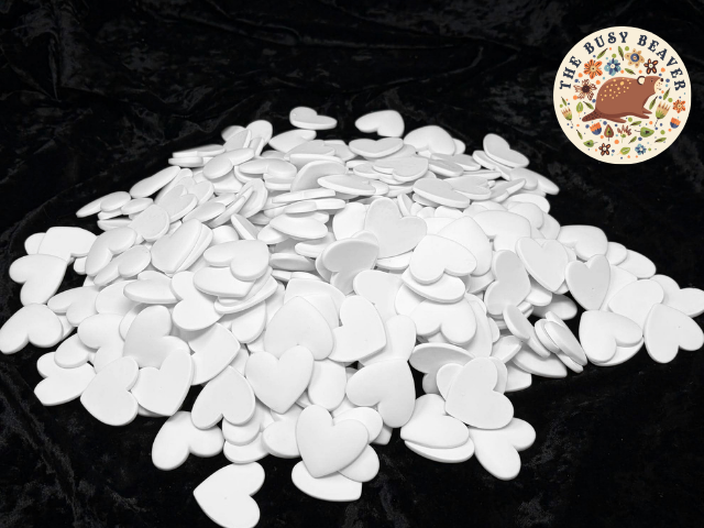 Bag of 300 white 37mm resin heart cabochons (cabs) shown as a pile on a black background