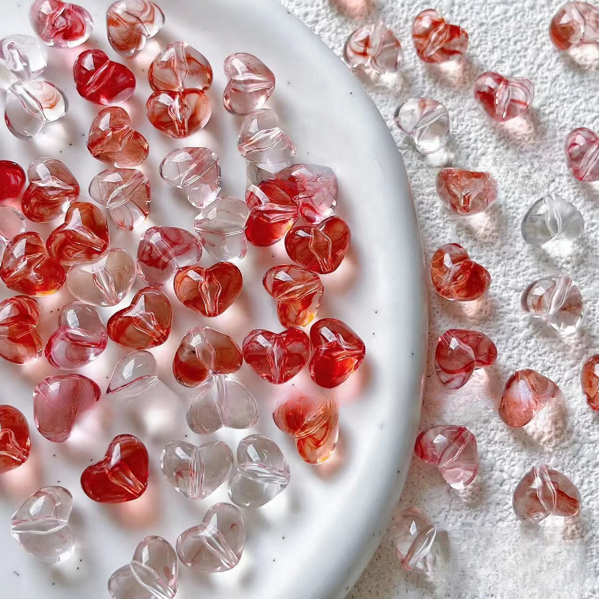 Bowl of 10 x 12mm red swirl heart acrylic beads with a marbled clear finish