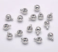 Pile of rhodium stopper crimp beads with loops on a pale background