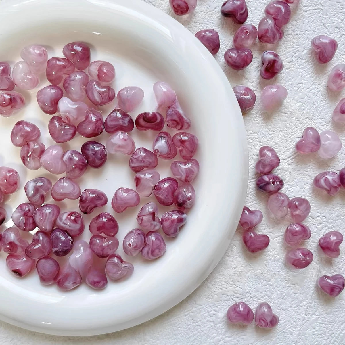 Bowl of 10 x 12mm rose swirl heart acrylic beads with a marbled clear finish