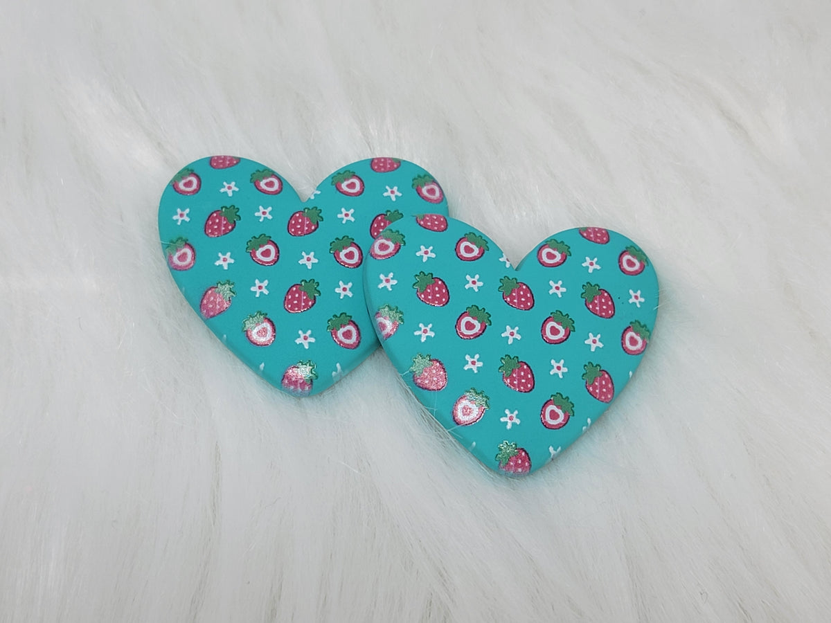 Pair of 37mm resin heart cabochons (cabs) in teal with a red strawberry and white flower pattern