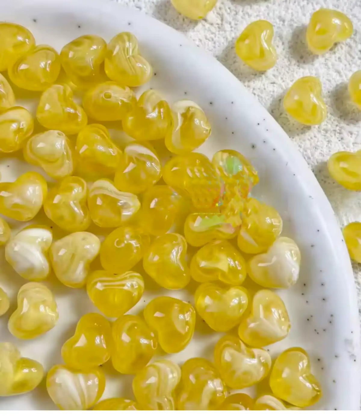 Bowl of 10 x 12mm yellow swirl heart acrylic beads with a marbled clear finish