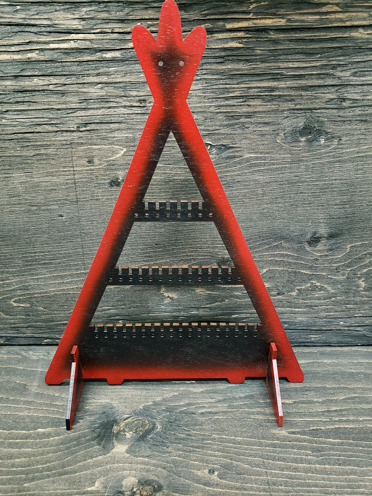 Tipi-shaped earring display rack with rows of holes, in red with a black centre