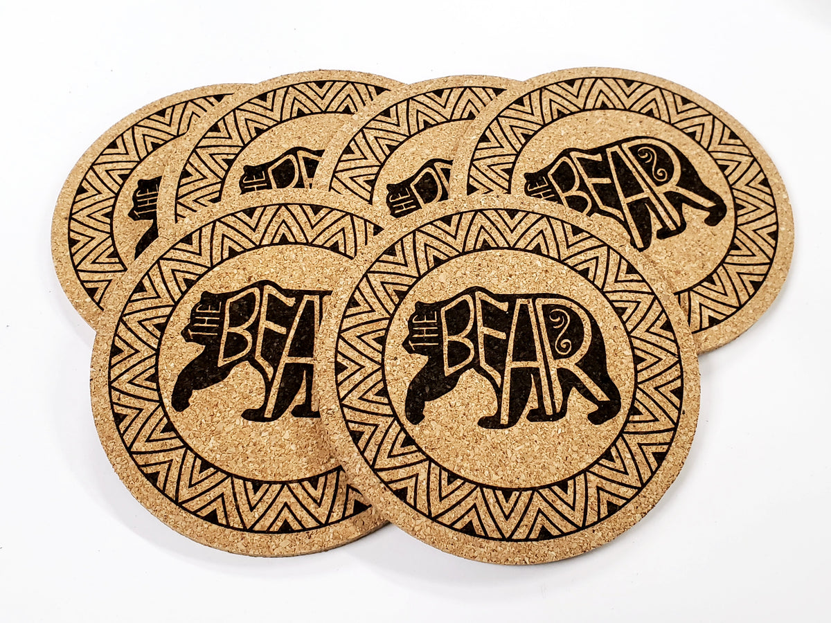 Stack of round cork coasters printed in black with a bear inside a patterned ring