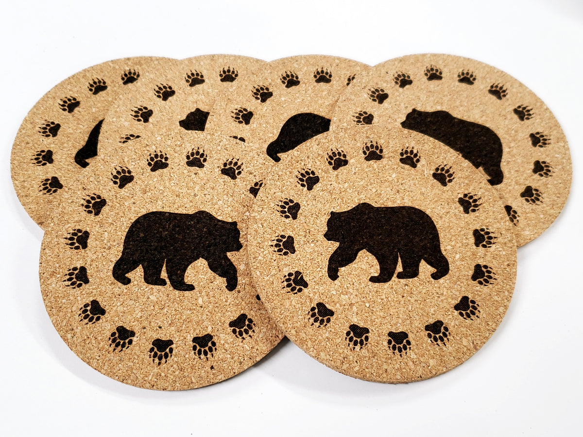 Stack of round cork coasters printed in black with a walking bear with a paw print border