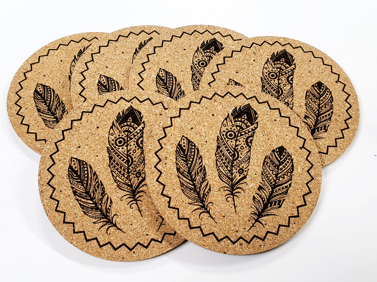 Stack of round cork coasters printed in black with three feathers in a scalloped border