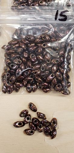 Bag of long magatama beads in purple rainbow marked #15, with loose beads in front