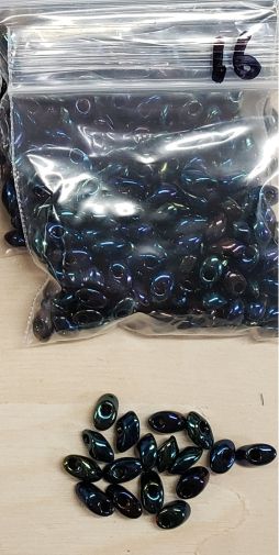 Bag of long magatama beads in blue rainbow marked #16, with loose beads in front