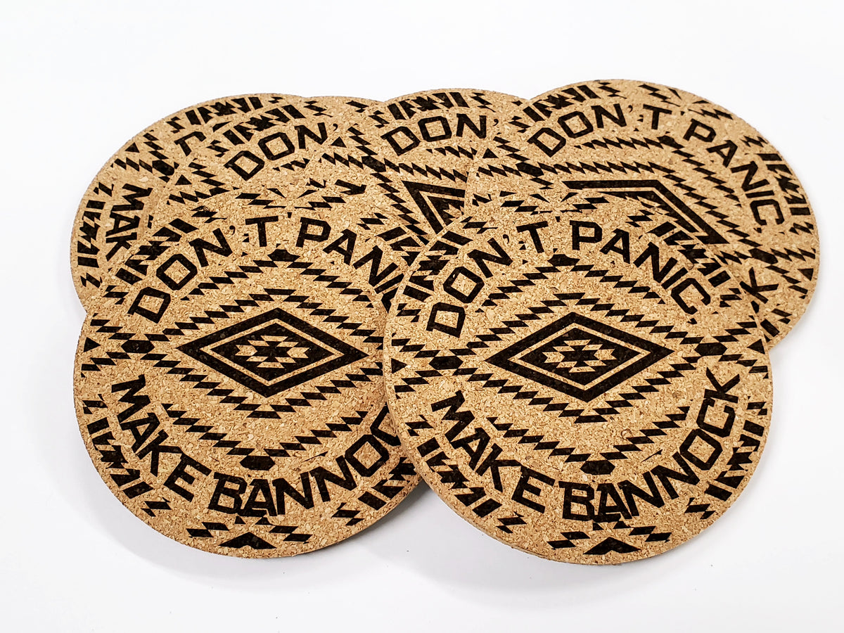 Stack of round cork coasters printed with the words 'Don't Panic Make Bannock' around a diamond