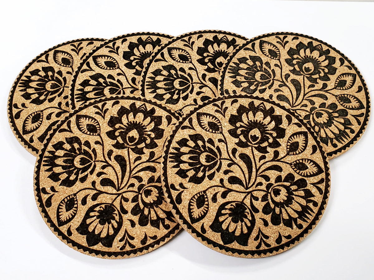 Stack of round cork coasters printed in black with a dense floral pattern