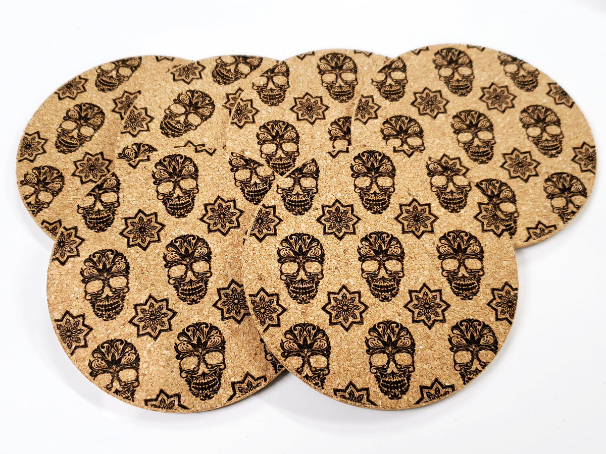 Stack of round cork coasters printed in black with a sugar skull pattern