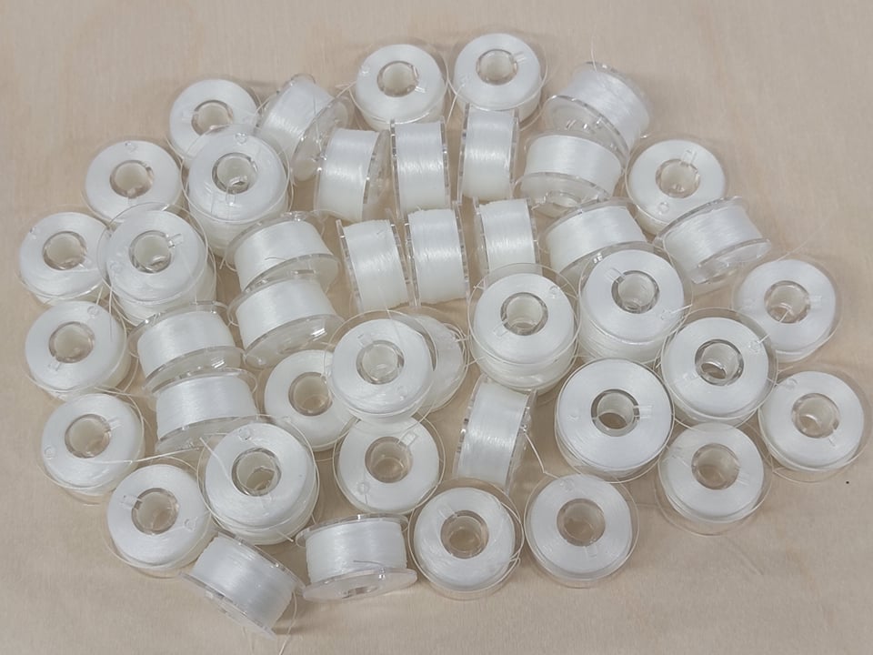 Pile of small white size OO Nymo thread bobbins, seen from above