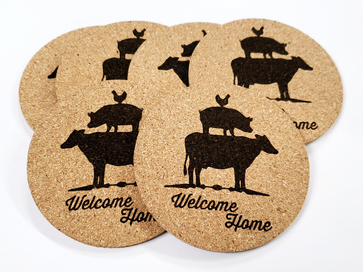 Stack of round cork coasters printed with the words 'Welcome Home' under stacked farm animals