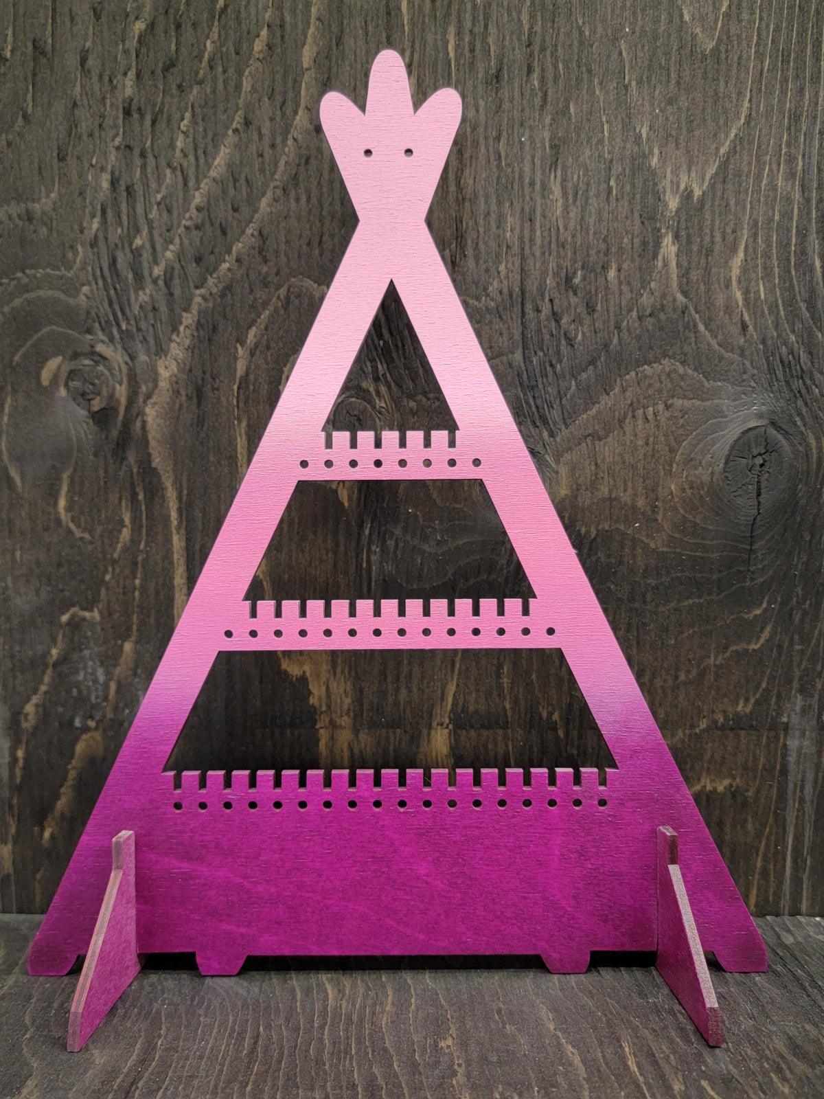 Tipi-shaped earring display rack with rows of holes, in light pink to pink to plum