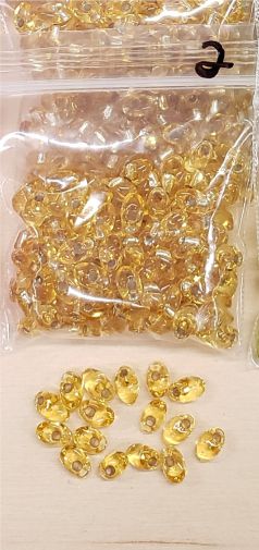 Bag of long magatama beads in gold marked #2, with loose beads in front