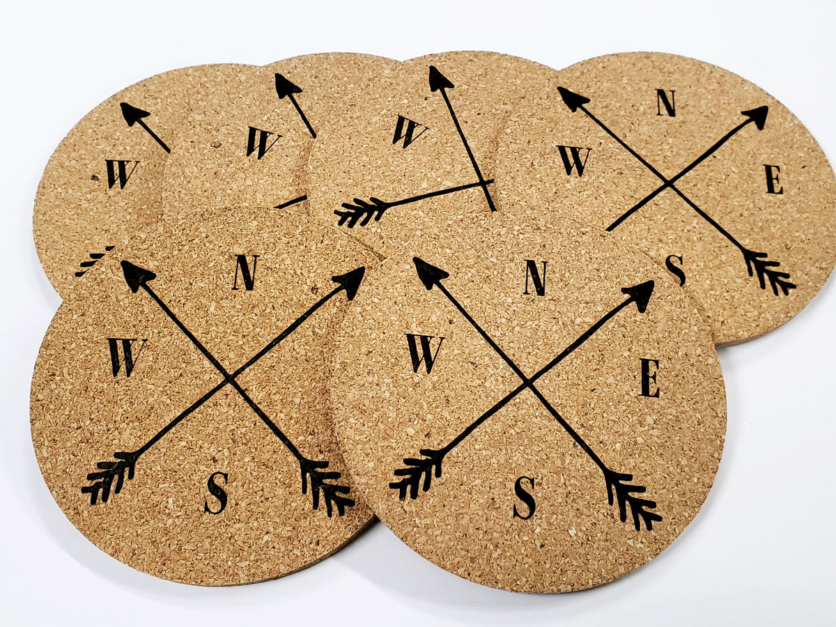 Stack of round cork coasters printed in black with a compass with crossed arrows