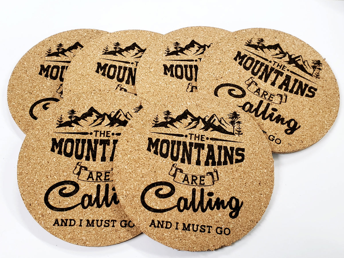 Stack of round cork coasters printed with the words 'The mountains are calling and I must go'