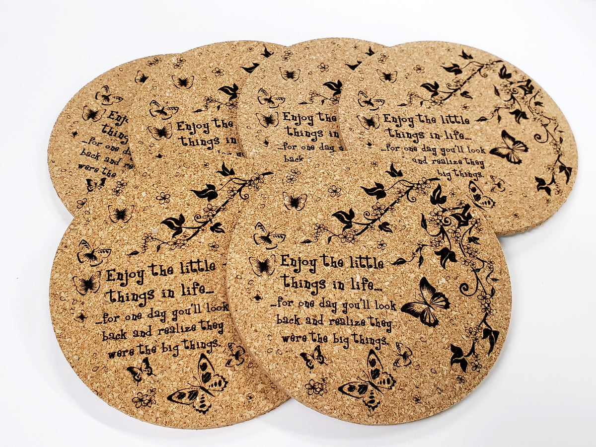 Stack of round cork coasters printed with the words 'Enjoy the little things' with butterflies