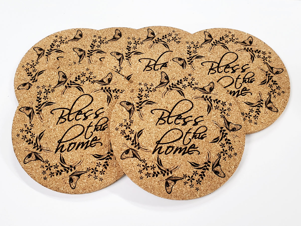 Stack of round cork coasters printed with the words 'Bless the home' in a floral wreath