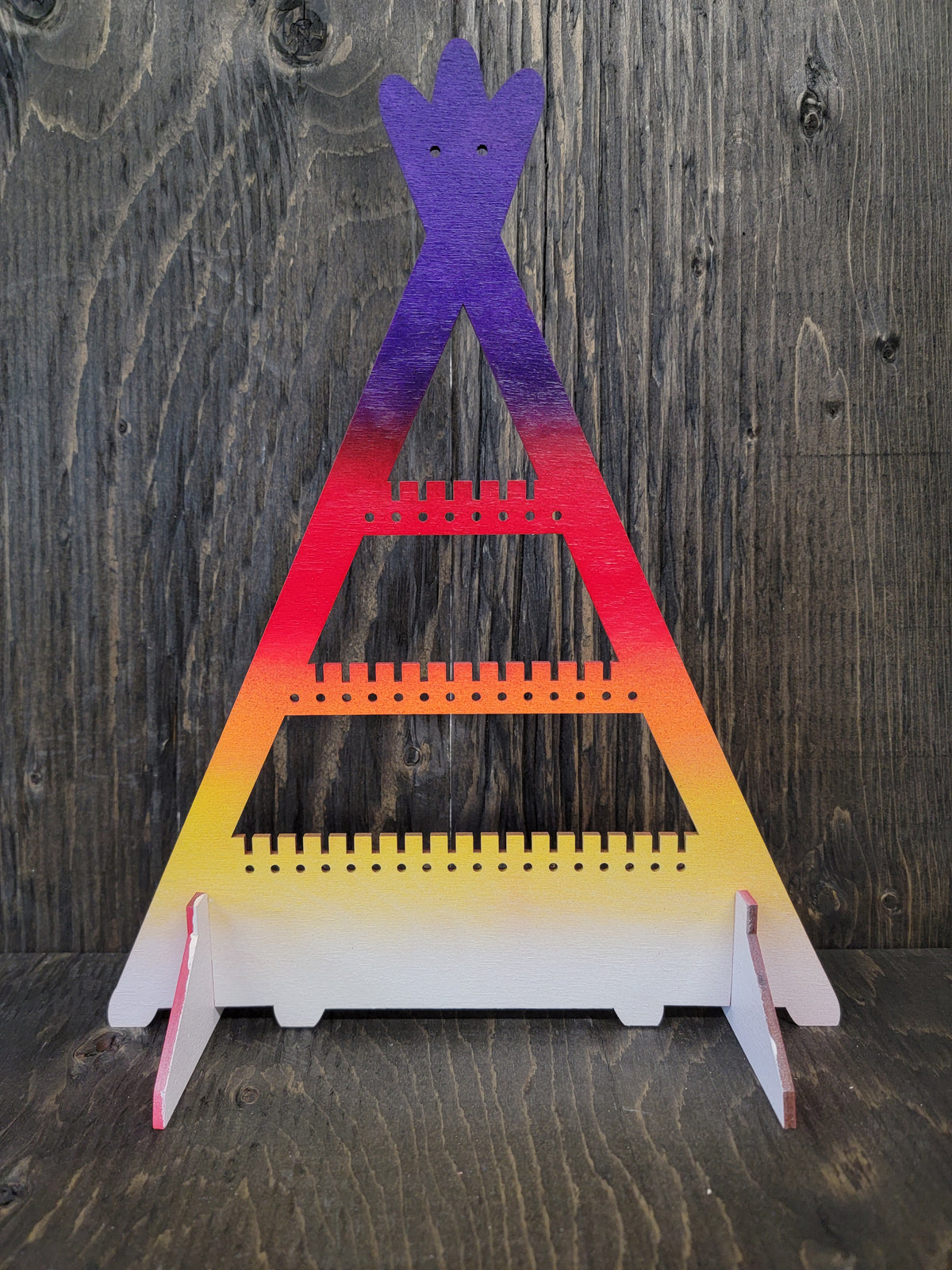Tipi-shaped earring display rack with rows of holes, in sunset purple, red, orange and yellow