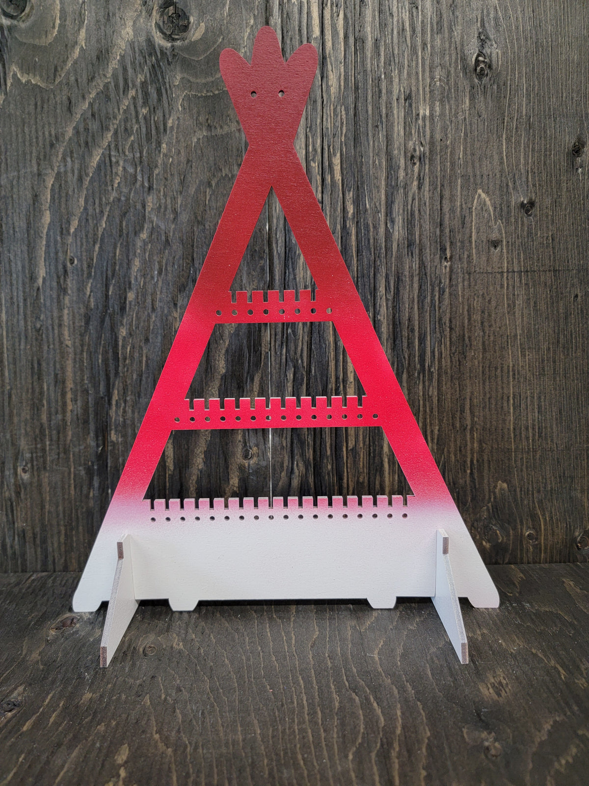 Tipi-shaped earring display rack with rows of holes, in dark red to red to white