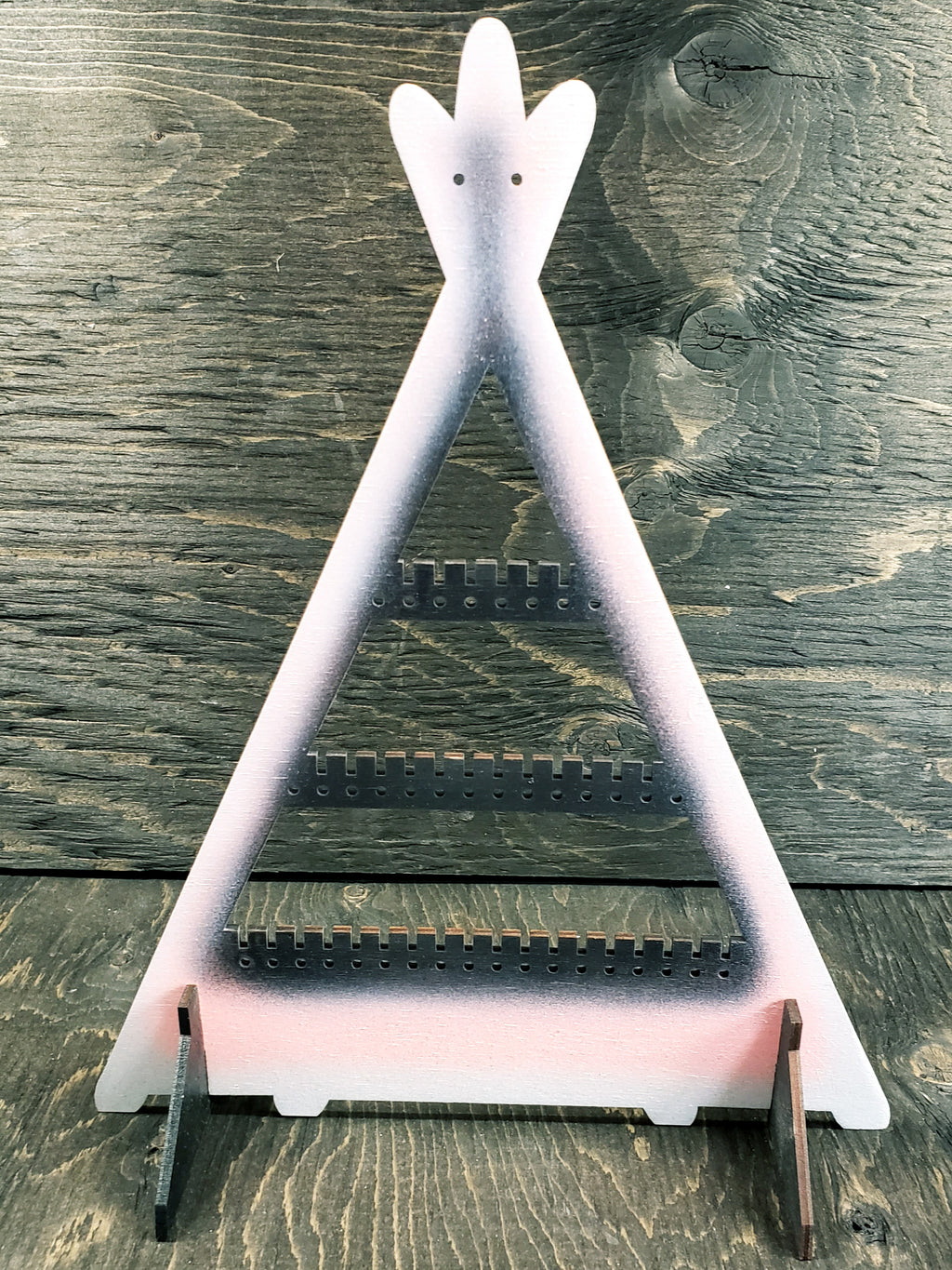 Tipi-shaped earring display rack with rows of holes, in white with a black centre