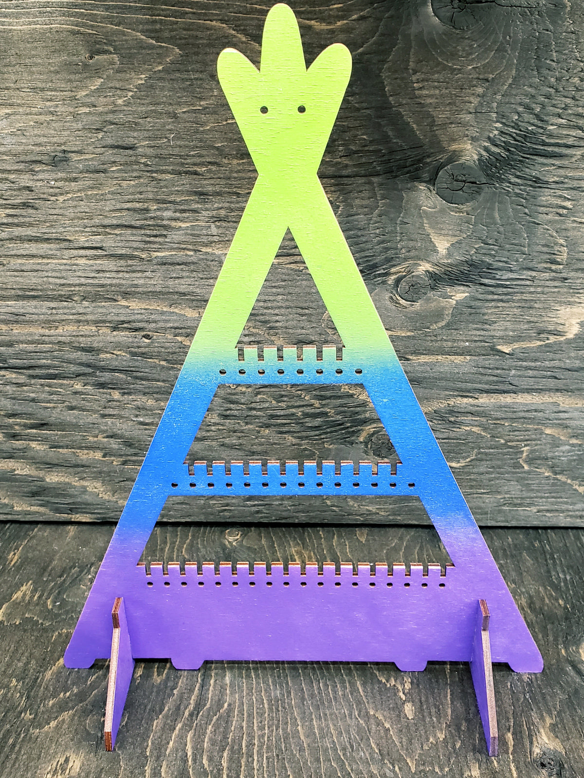 Tipi-shaped earring display rack with rows of holes, in green to blue to purple