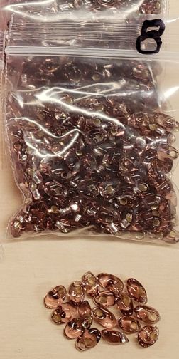 Bag of long magatama beads in amethyst marked #8, with loose beads in front